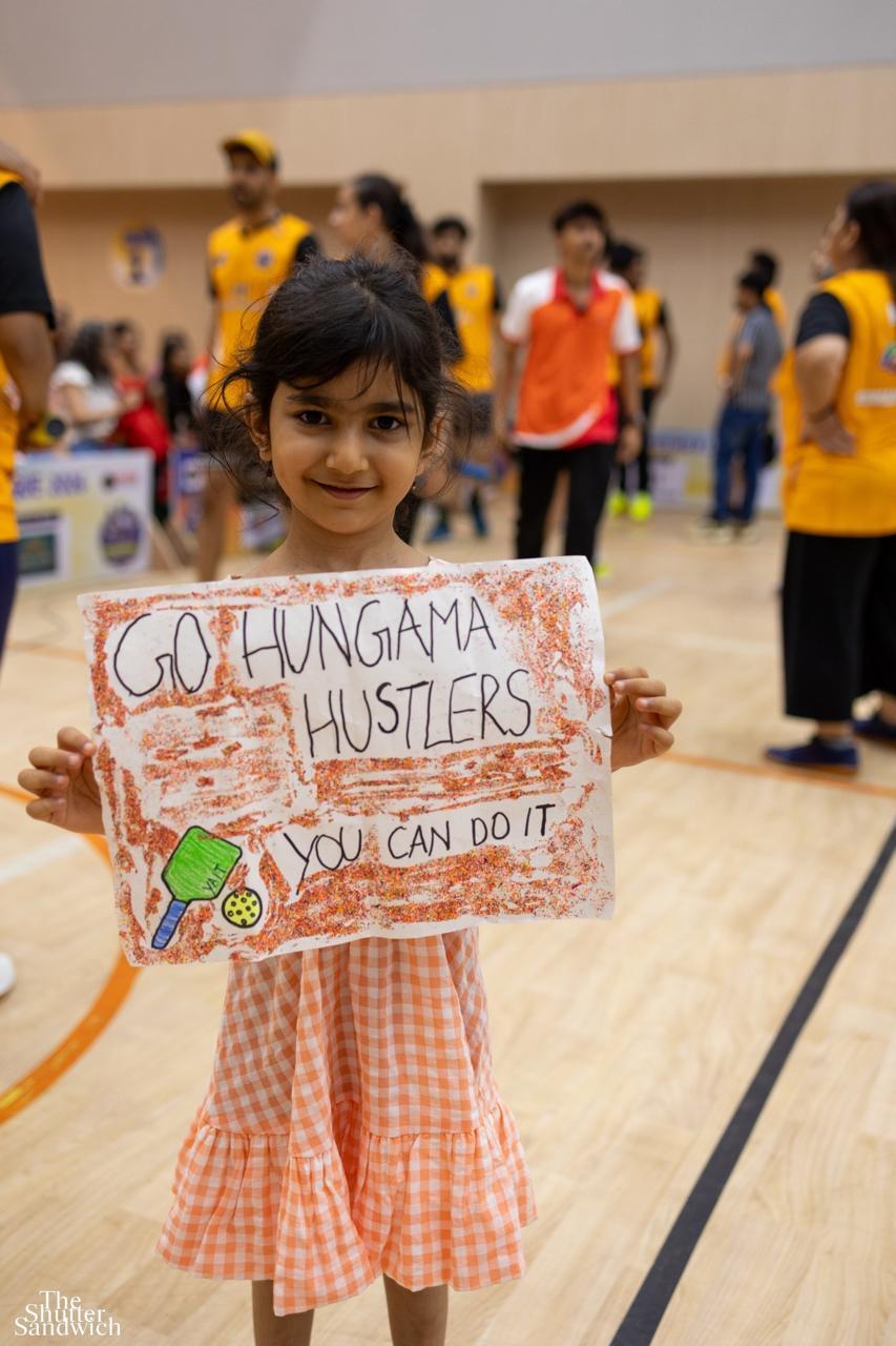 Young fan holding a handmade 'Go Hungama Hustlers' sign