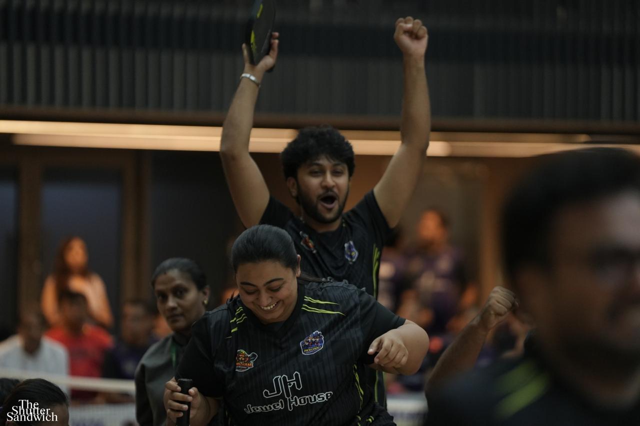 Player erupting in shout of victory, arms raised, paddle held high